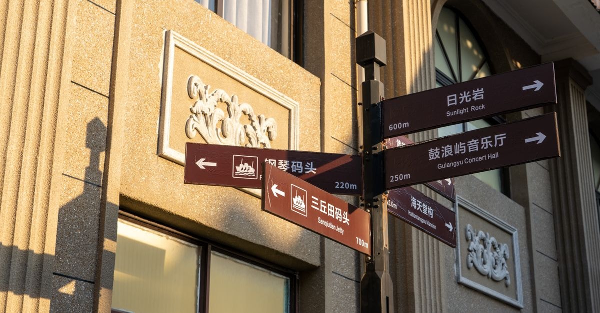 A Slow Weekend in Tianjin: A Travel Guide to Coastal Calm and Old Streets Street signposts guide tourists to notable Gulangyu Island attractions under soft sunlight.