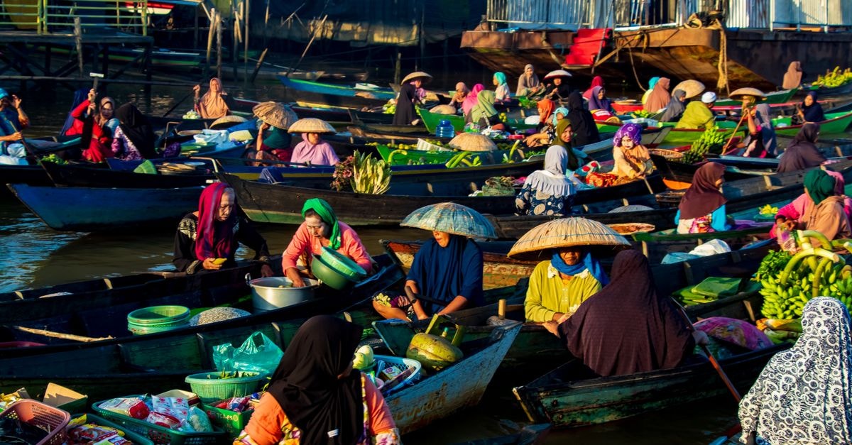 Colorful floating market in Banjarmasin with local merchants selling fresh goods at sunrise.