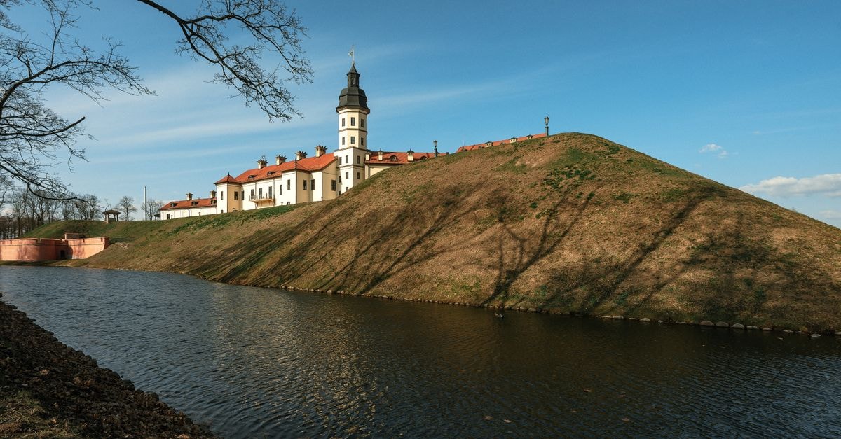 A serene landscape of the historic Niasvizh Castle, Belarus, under a clear spring sky.