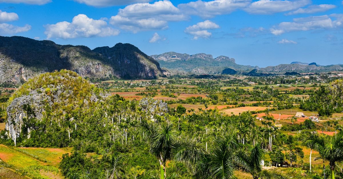 Breathtaking view of Vinales Valley with vibrant greenery, mountains, and clear blue skies.