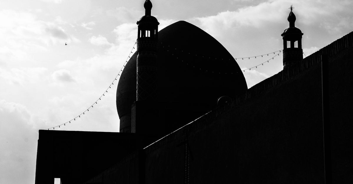Sayeh Saray, Kashan — A Restored 200-Year-Old House in the Old City Black and white silhouette of a mosque dome and minarets in Kashan, Iran, against a cloudy sky.