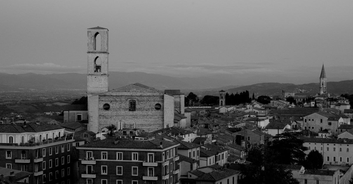Aerial black and white view of a historic Italian cityscape featuring medieval architecture and bell towers.