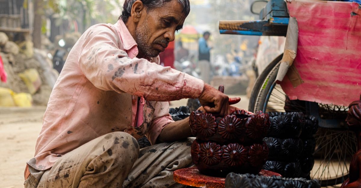 A Slow Travel Guide to Begusarai, Bihar South Asian potter in a bustling street market carefully crafting traditional terracotta pottery.