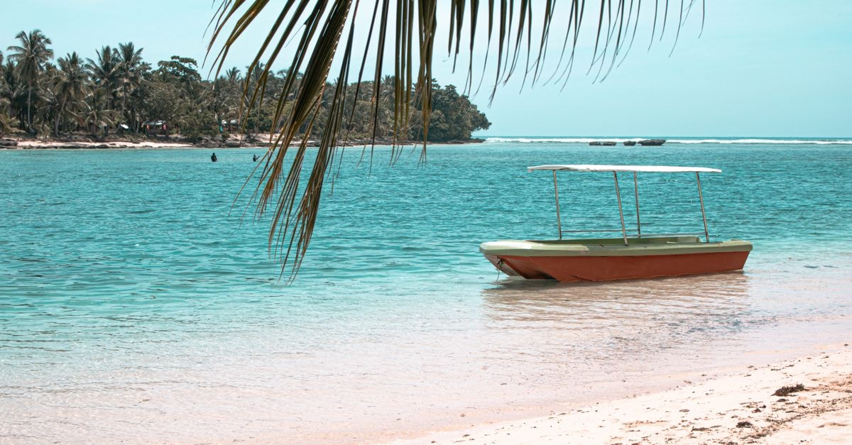 Lautoka Travel Guide: Planning Tips, Costs and Things to Do A peaceful tropical scene in Baganga, Philippines, showcasing clear waters, a docked boat, and coconut trees.