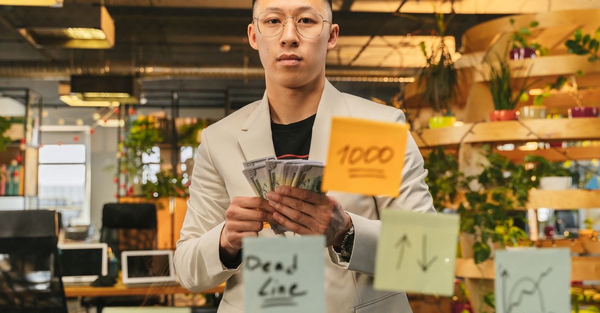 National Pension Service lifts Home Depot stake as shares trade near 52-week low A businessman in a suit stands in a vibrant office, holding cash with sticky notes on glass.