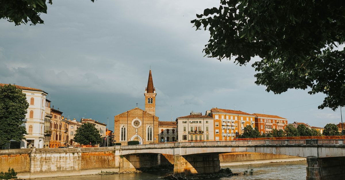 Beautiful view of a historic bridge over the river in Verona, Italy, under a cloudy sky.
