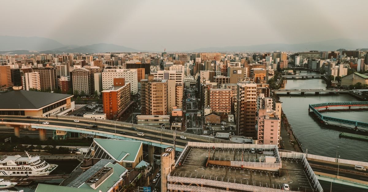 Hotel Resol Hakodate in Hokkaido: Morning-Market Front Door Aerial view of a bustling cityscape featuring high-rise buildings and a scenic waterway.