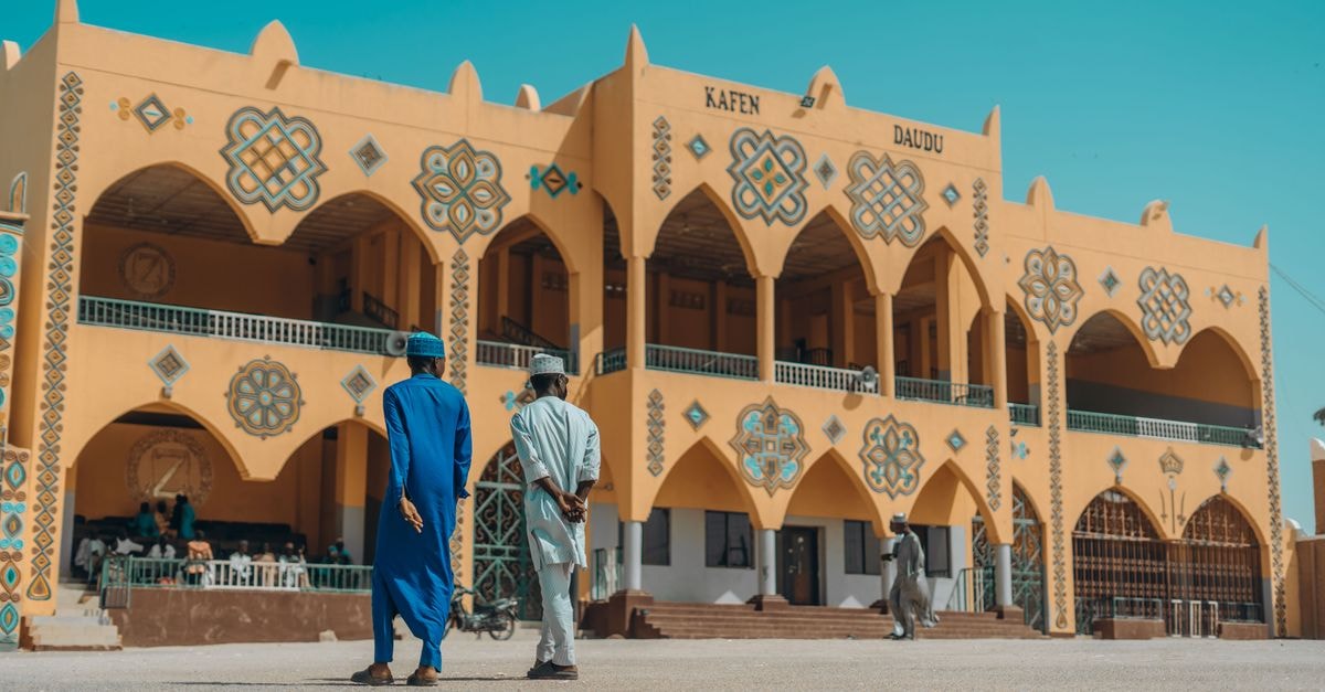 Colorful traditional Nigerian building exterior with two people walking.