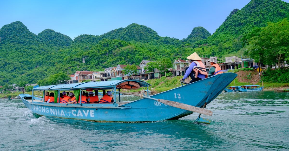 Tourists enjoy a scenic boat ride in Phong Nha Ke Bang National Park, showcasing vibrant landscapes.