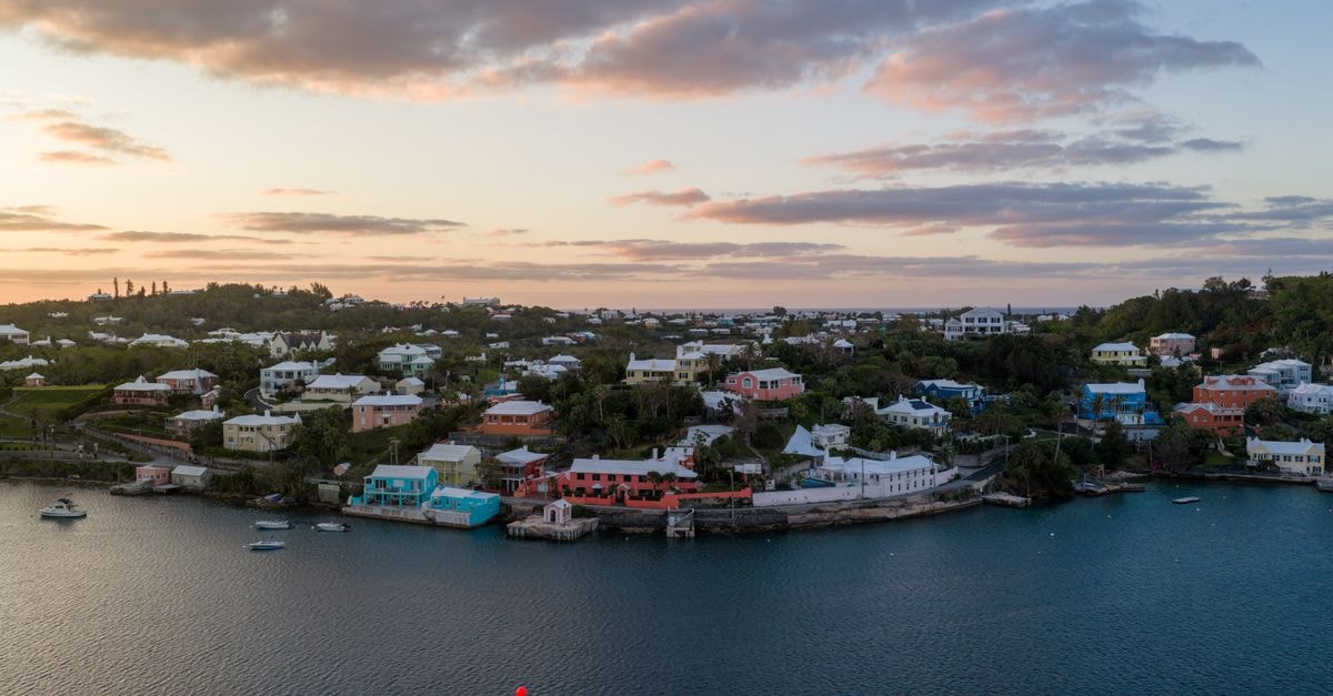Ocean Paradise Vacation Rental in Bodden Town: Cayman Island Escape Aerial view of Bermuda's coastline at sunrise showcasing vibrant houses and calm waters.