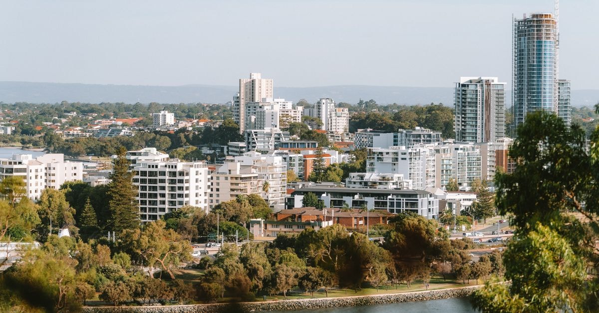 A beautiful day view of Perth city skyline with lush greenery and Swan River.