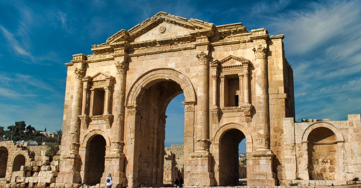 Ruins Wall Hotel & Hostel in Jerash: Steps to the Ancient City Gates The ancient Arch of Hadrian stands tall in Jerash, a significant Roman archaeological site in Jordan.