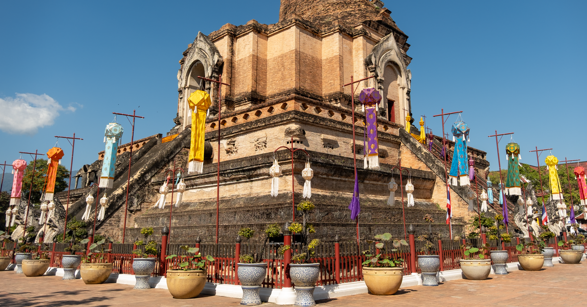 Lamphun Travel Guide: Royal Roots and Mountain Air Stunning view of the historic Wat Chedi Luang temple with vibrant flags in Chiang Mai, Thailand.