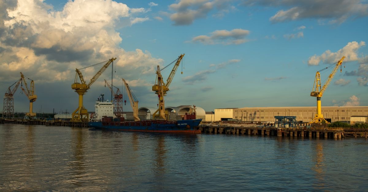 A scenic view of an industrial harbor with cranes and a cargo ship during the day.