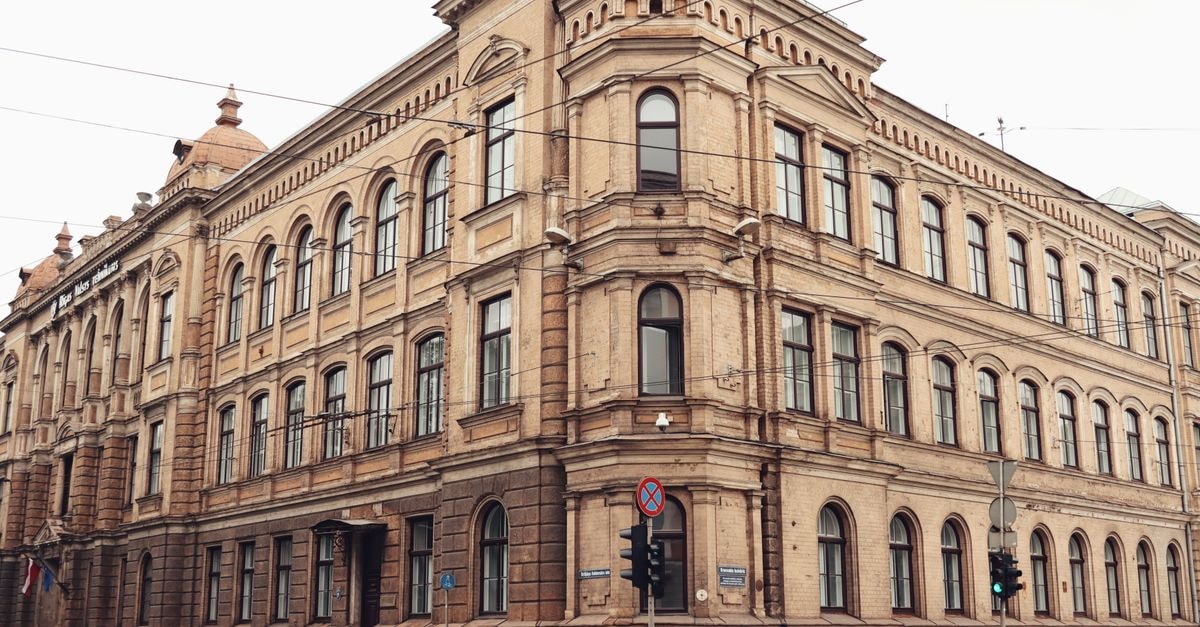 Riga travel guide: a quietly captivating Baltic capital Elegant historic building facade in Riga's old town with a person walking by.