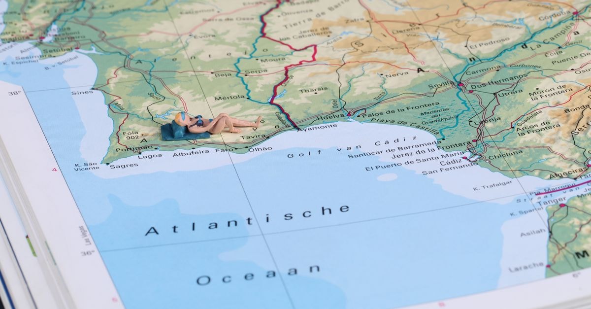 Owo Travel Guide: Planning Tips, Costs and Things to Do A creative scene with a miniature figure sunbathing on a detailed geographic map of Spain's coastline.
