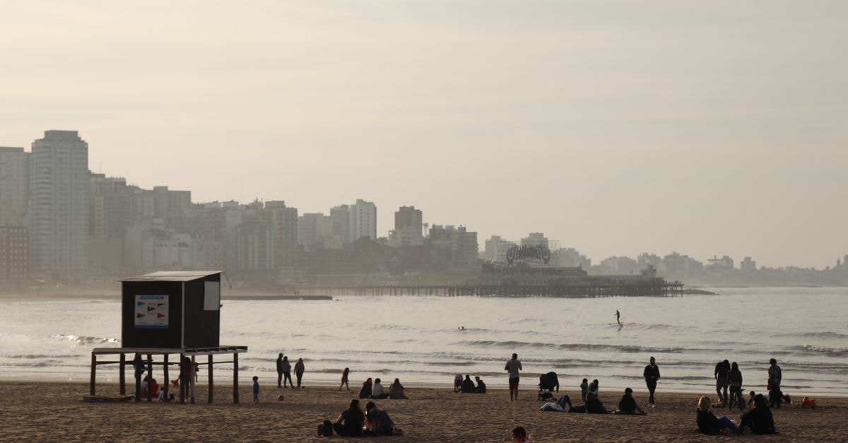 Mar del Plata Travel Guide: Atlantic Coast Rhythm and Easy Moves Sunny day at Mar del Plata beach with tourists enjoying the seashore and city skyline.