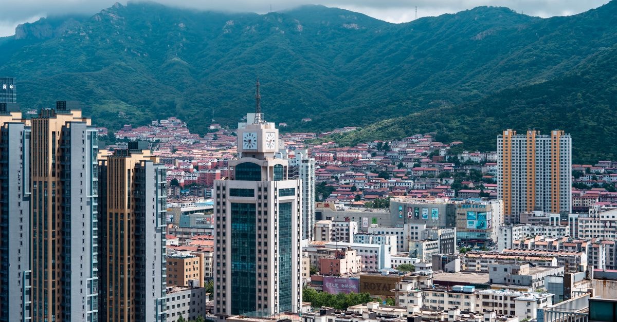 Huamao International Hotel, Huangshan — Qianyuan South Road Stay Base Stunning aerial view of Qingdao's modern skyline with mountains in the backdrop.