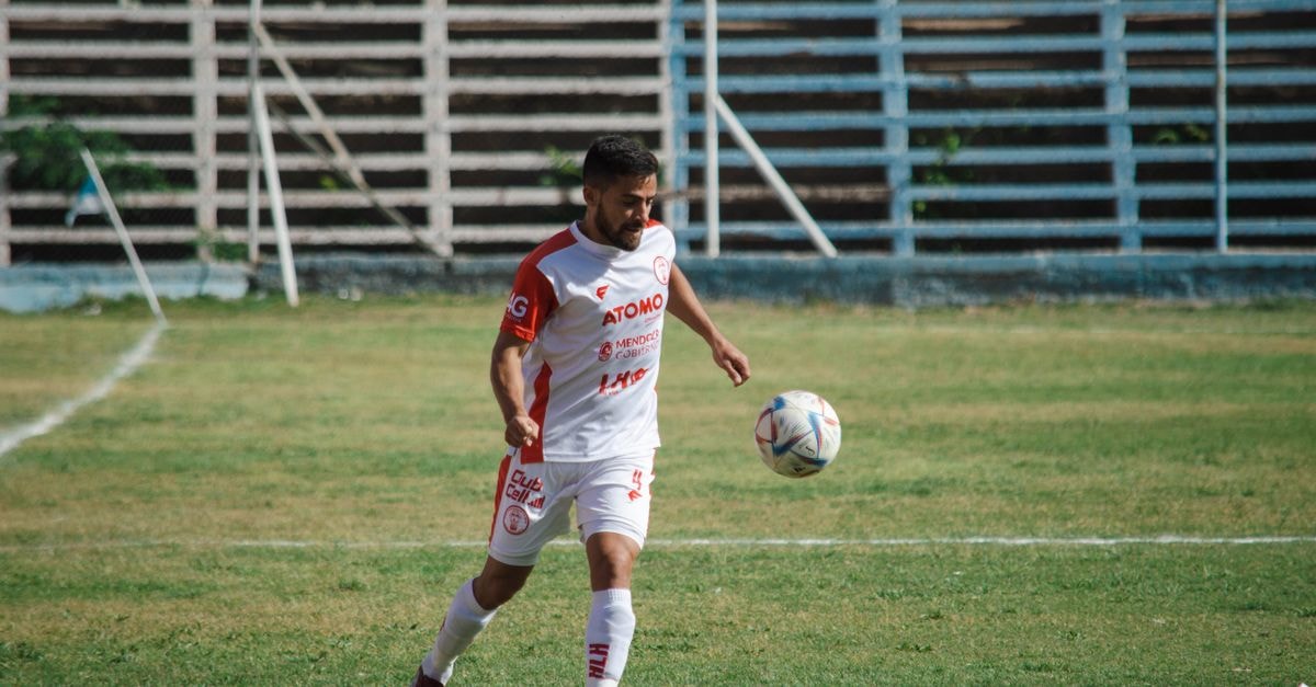 Soccer player in white kit playing on a field in Mendoza, Argentina.