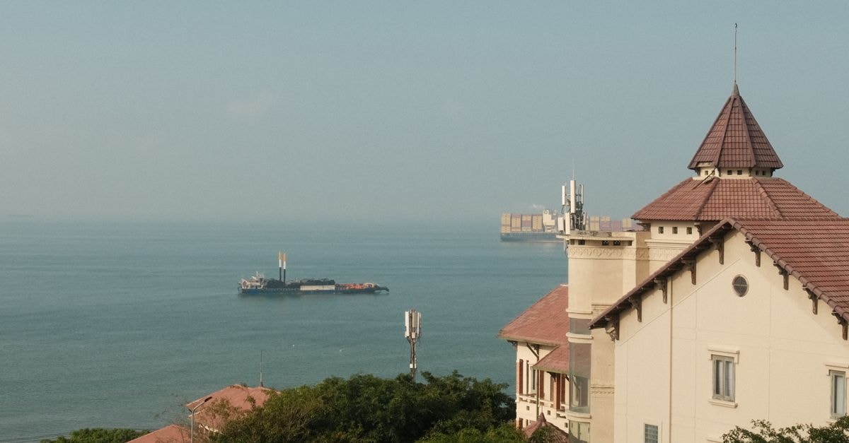 Serene coastal scene with a ship and historic architecture in Vũng Tàu, Vietnam.