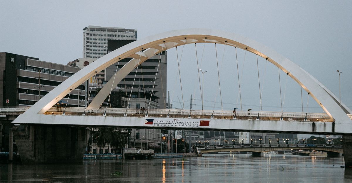 Manila Travel Guide for September 2026: Planning Tips and Costs A view of a modern arch bridge spanning over the Pasig River in Manila during daytime.