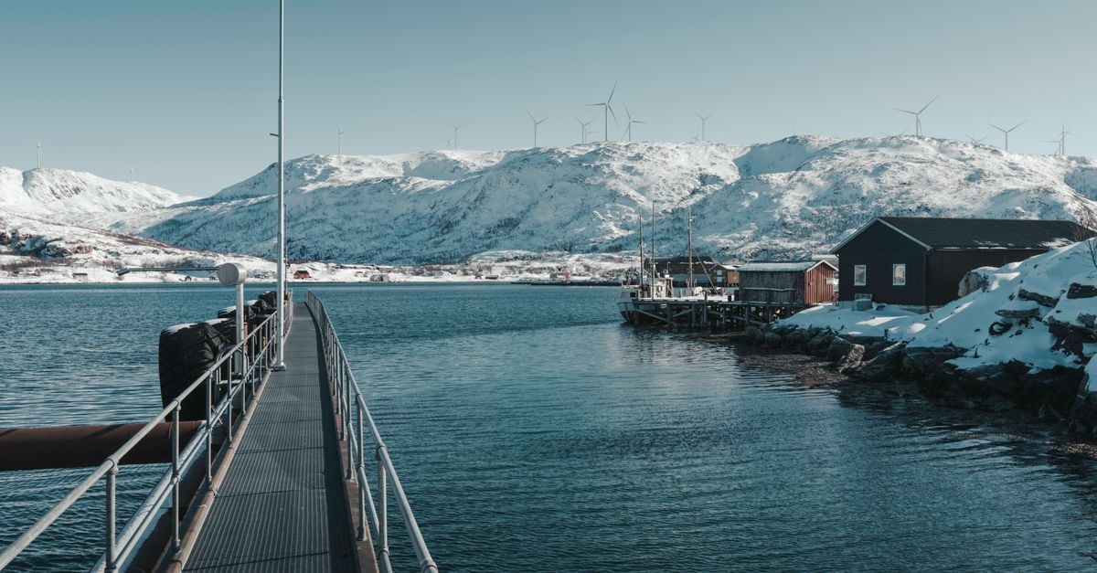 Nuuk Travel Guide: Planning Tips, Costs and Things to Do Scenic snowy fjord in Northern Norway with wind turbines and calm waters.