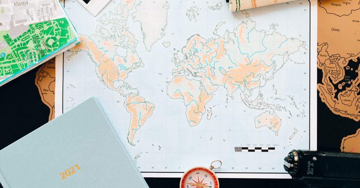 Bimbo Travel Guide: Planning Tips, Costs and Things to Do Flat lay of travel essentials including a world map, compass, and planner, perfect for planning your next adventure.