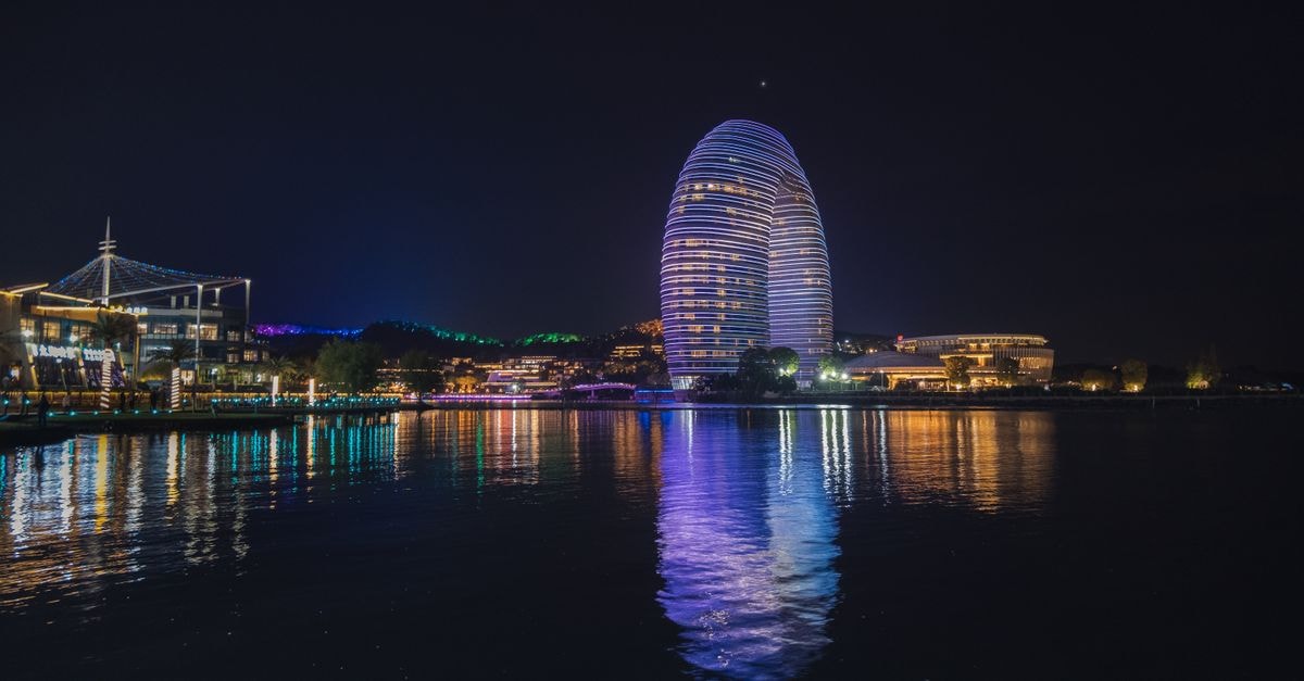 Huzhou Travel Guide: How to Move and What to Eat Illuminated Sheraton Huzhou Hot Spring Resort reflecting in water at night in China.
