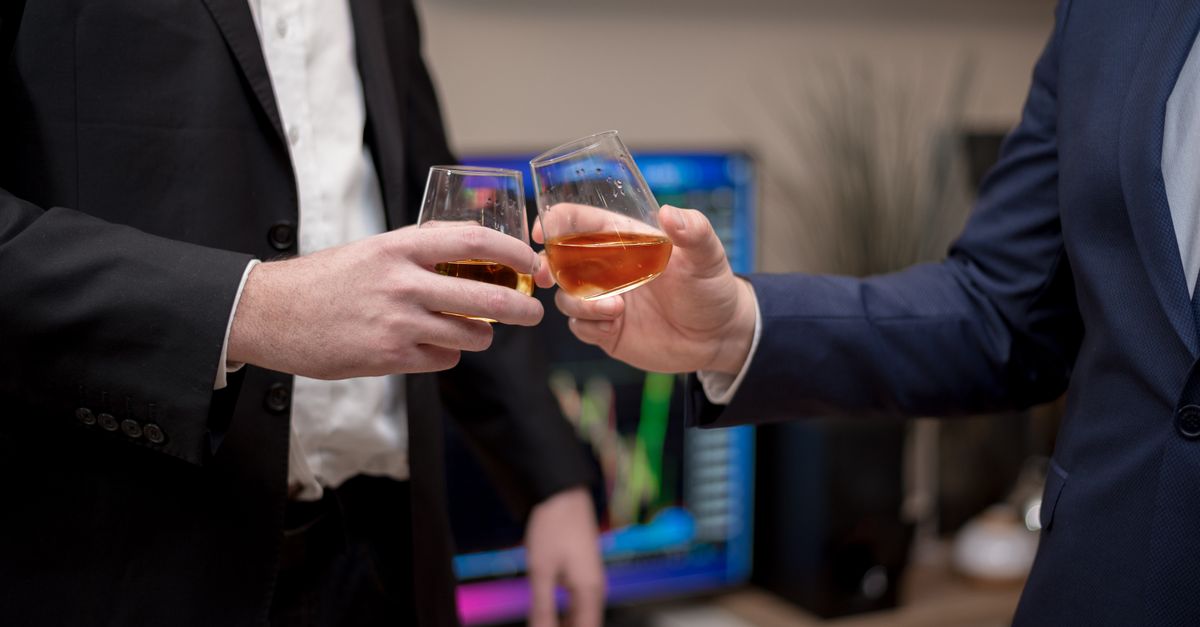 Shark Tank stars headline entrepreneur advice, $10M whisky deal and India Season 6 push Two businessmen in suits toasting with drinks in an office environment.