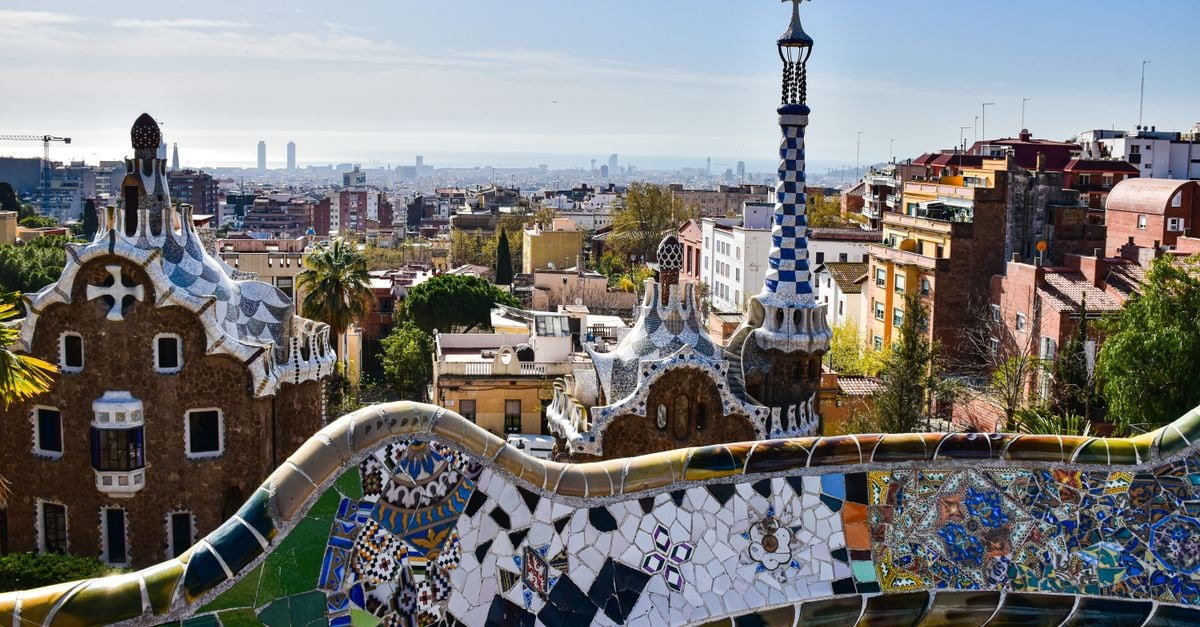 Gaudí's iconic mosaic architecture in Park Güell with a view of Barcelona's cityscape.