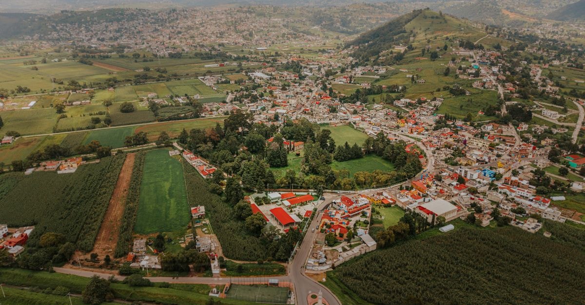 Panoramic aerial image of Santiago Tianguistenco with lush green fields and distant mountains.