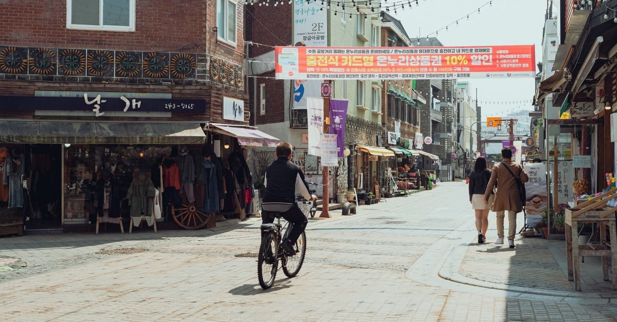Holiday Inn Express Suwon Ingye: A Smart City-Center Base Discover the lively street scene in Suwon-si with local shops and cyclists, capturing the essence of Korean urban life.