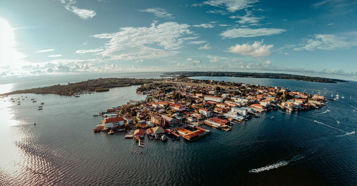 Belize City Travel Guide: Planning Tips, Costs and Things to Do Captivating aerial view of a vibrant island town surrounded by sparkling blue waters under a clear sky.