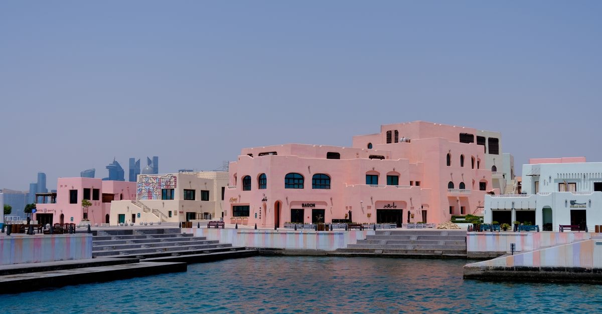 Park Hyatt Doha in Qatar: A Luxury Retreat Steps from Souq Waqif Pastel-colored buildings along a waterfront in Doha, Qatar with a city skyline backdrop.