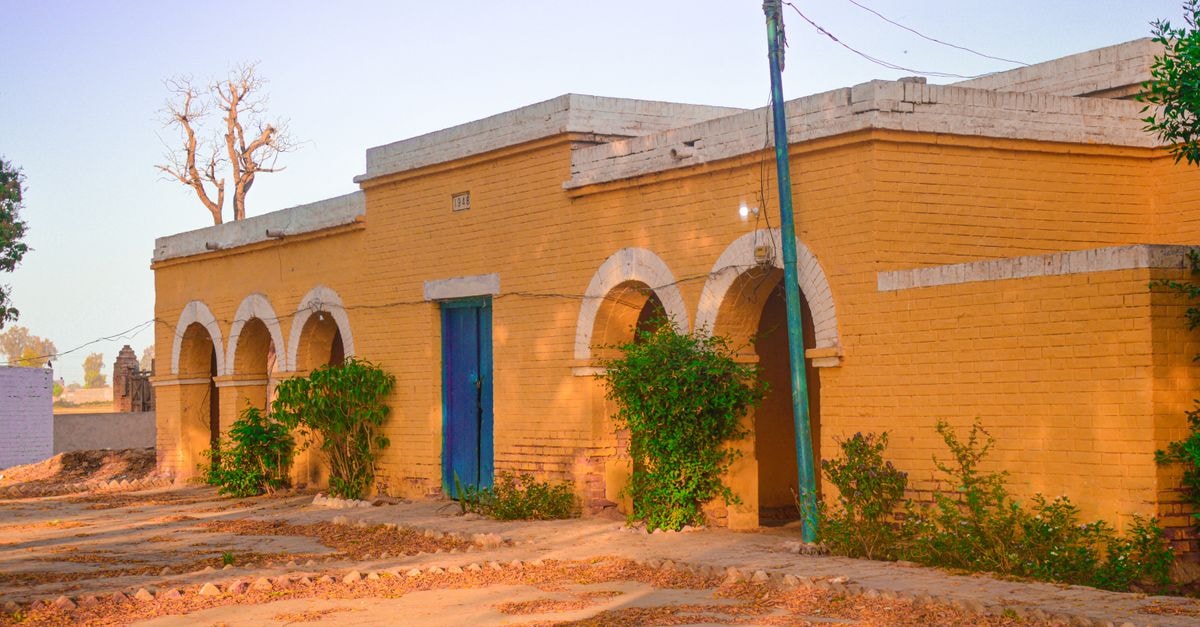Okara Travel Guide: A Quiet Stop on Punjab's Heritage Trail Charming rural brick building with arches and greenery, showcasing traditional architecture.