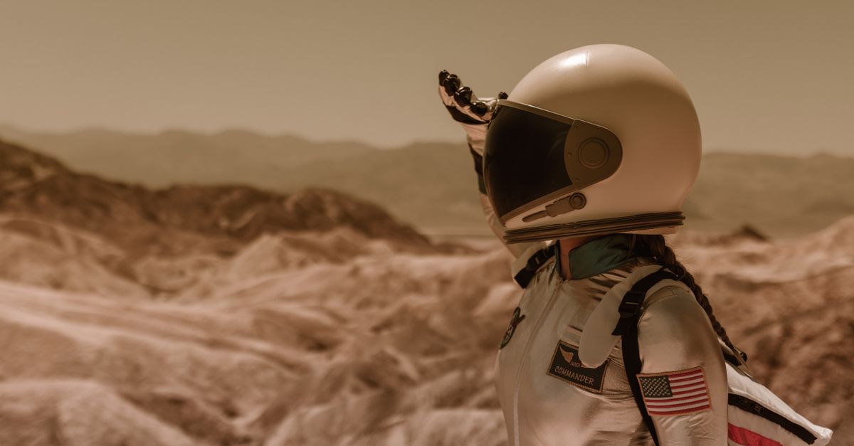 SpaceX Pushes Starship Flight 13 to Friday as Short Bets Climb to $25 Billion An astronaut in a space suit explores a desolate rocky landscape under a bright sky.