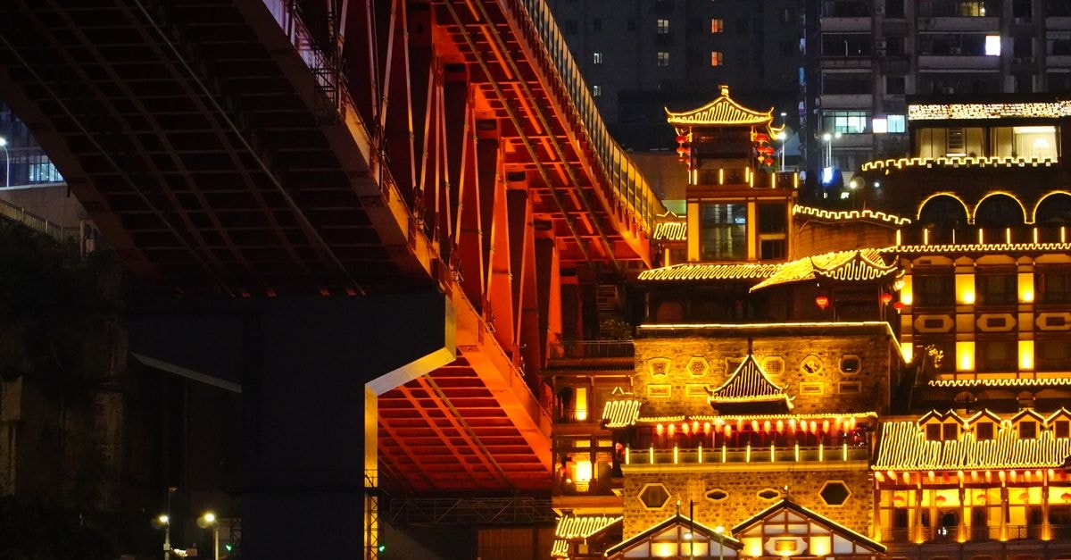 Night view of a beautifully lit traditional building under a modern urban bridge.