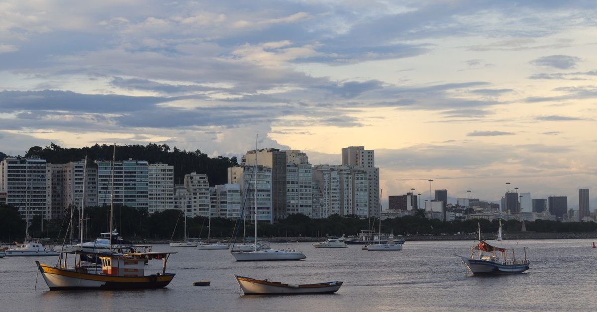 Porto Alegre Travel Guide: Where the Guaíba Shapes the City Evening view of fishing boats in a harbor with cityscape and high-rise buildings in the background.