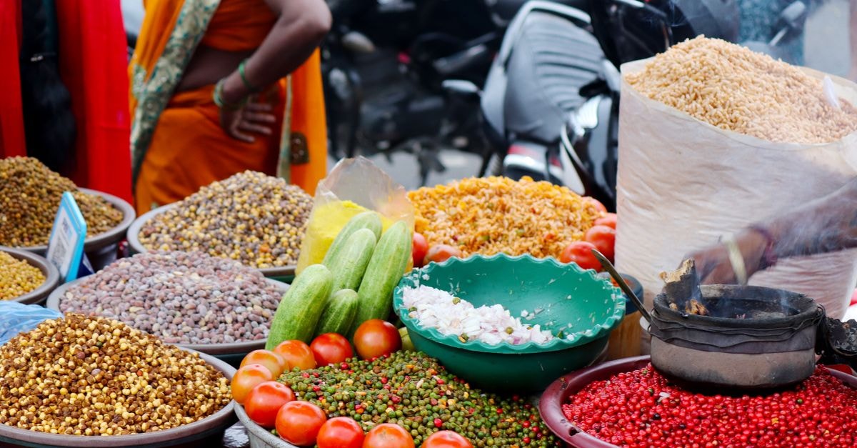 Gajuwaka Travel Guide: Climate Context and India's Food Traditions Colorful outdoor market stall featuring spices, tomatoes, cucumbers, and other vegetables.