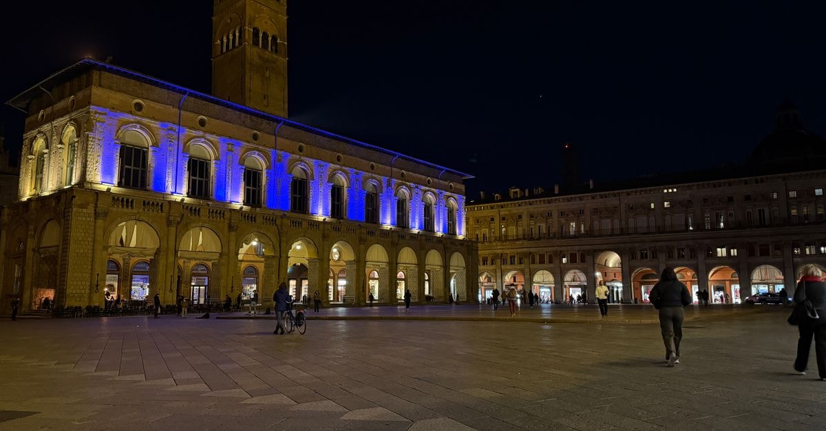 Stunning night view of Palazzo del Podestà, Bologna, illuminated with vibrant lights.