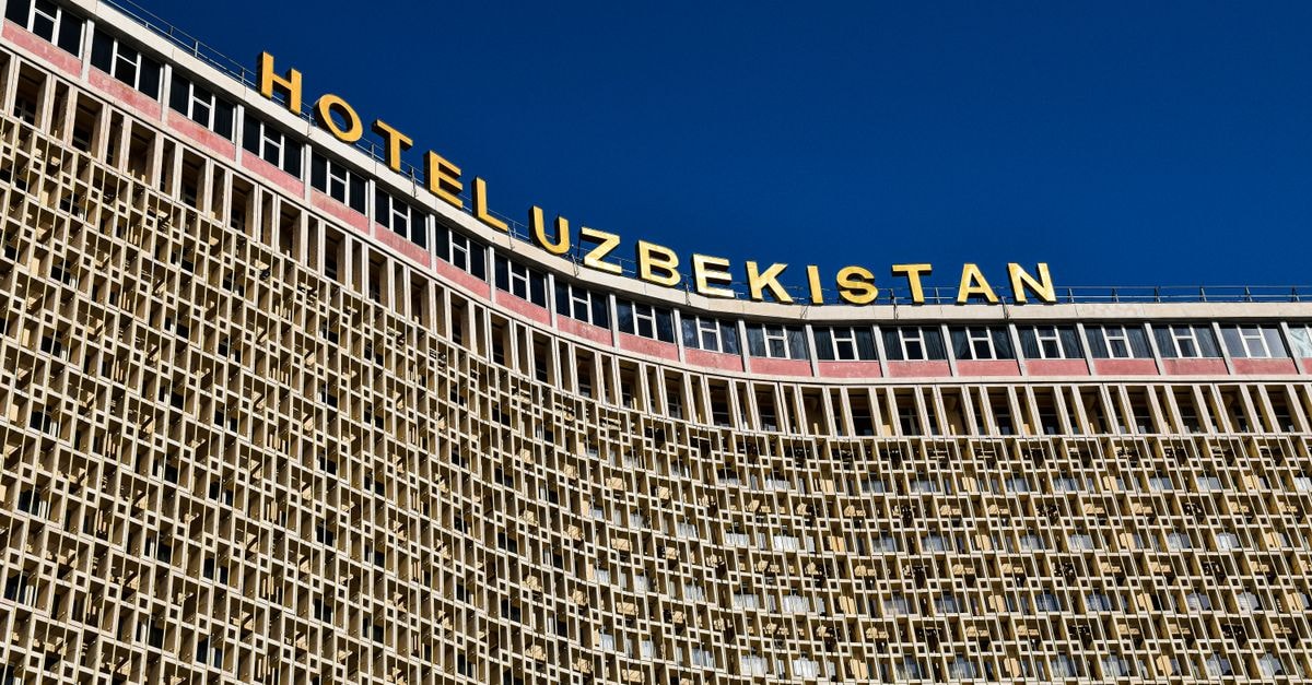 Low angle shot of Hotel Uzbekistan facade against a clear blue sky.