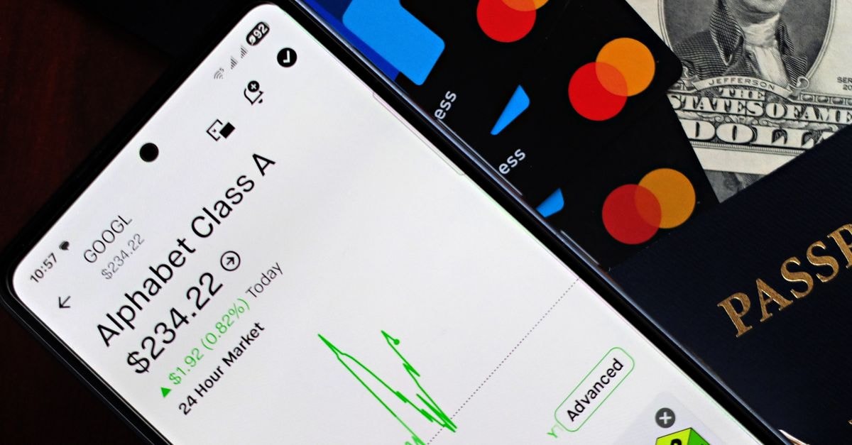 Qualcomm slides on UBS price-target cut as smartphone chip shipments weaken A smartphone displaying Alphabet stock price alongside credit cards, cash, and passport.