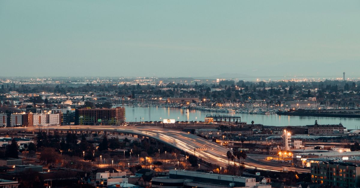Stunning cityscape at dusk with long exposure showing illuminated roads and urban landscape near water.