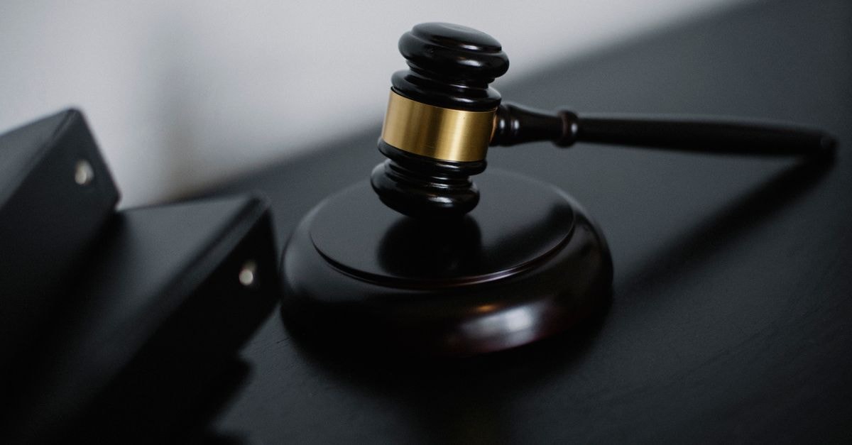 xAI 第二次阻止明尼蘇達州 AI 裸體生成法失敗 從高角度拍攝的閃亮木質儀式槌,帶有金色裝飾,放置在法官席附近,旁邊有文件資料夾