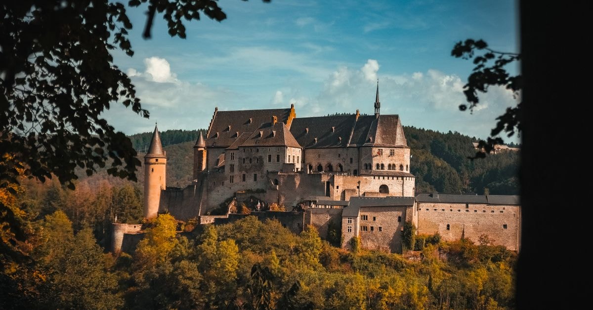 Luxembourg Travel Guide: Planning Tips, Costs and Things to Do Capture of Vianden Castle surrounded by lush landscapes during a radiant day in Luxembourg.