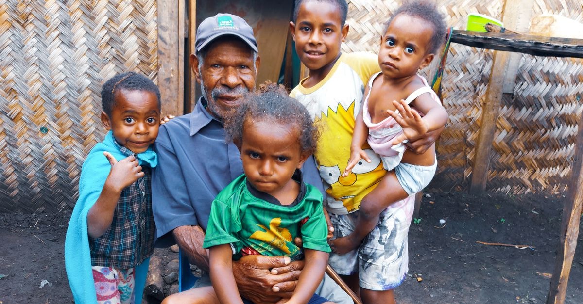 A warm family portrait with a grandfather and children outdoors, showcasing love and togetherness.