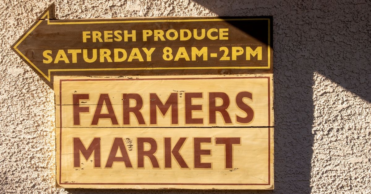 Chandler Travel Guide: Getting Around, Eating Well, and Slowing Down Brightly painted farmers market sign indicating fresh produce times.