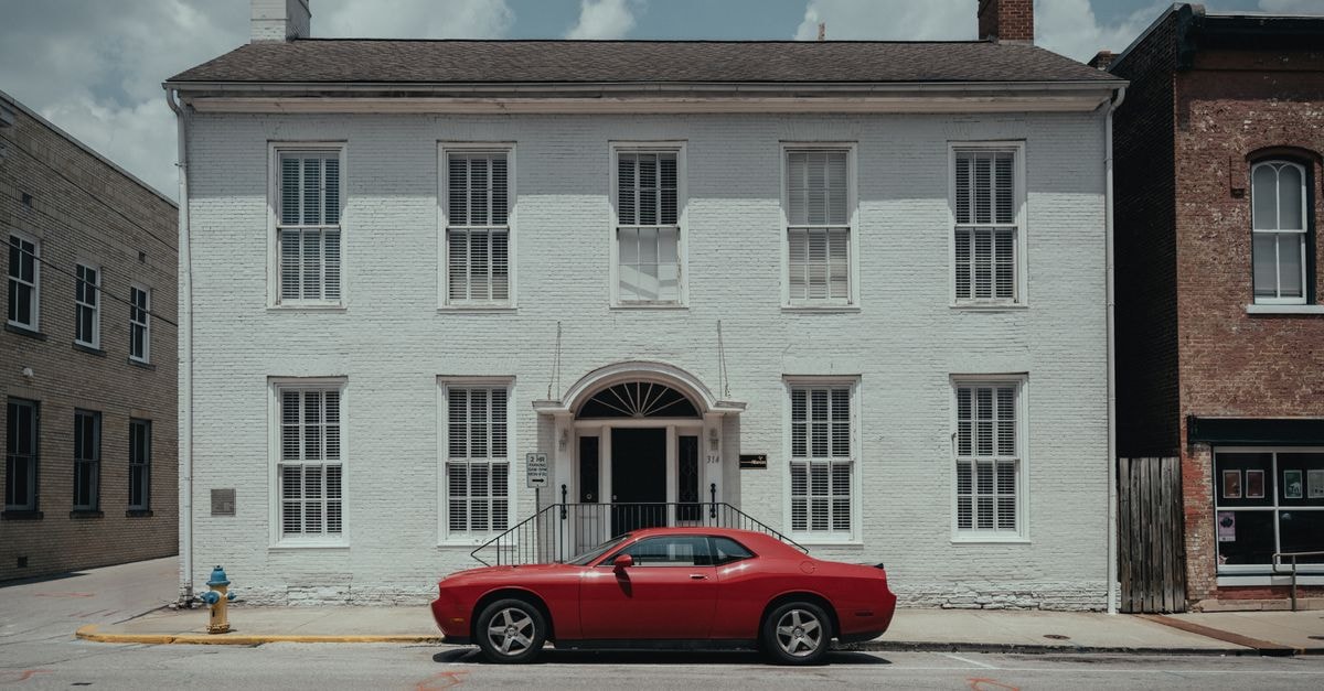 A Frankfort, Kentucky Travel Guide for Bourbon, Bluegrass and Riverfront Strolls A red Dodge Challenger parked in front of historic white building in Frankfort, KY.