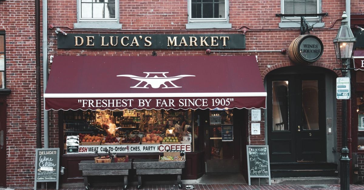 Historic De Luca's Market facade showcasing fresh produce and cozy urban atmosphere.