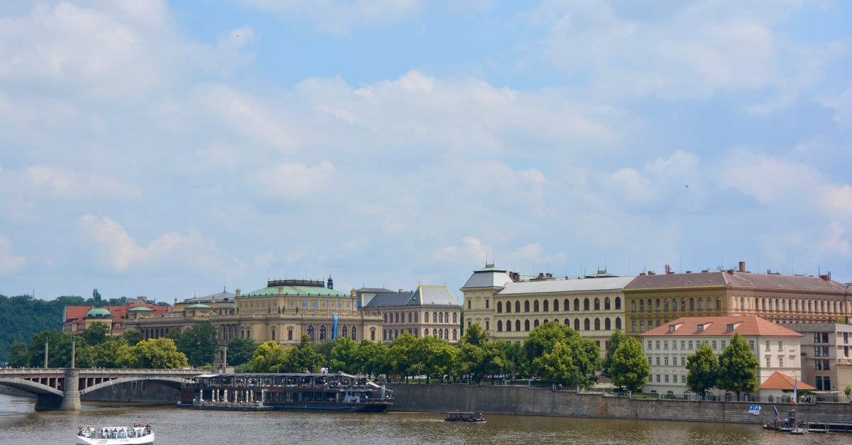 Iron Gate Hotel & Suites, Prague — 71 Rooms in a UNESCO-Listed Hideaway A picturesque view of Prague with the Vltava River, historical buildings, and a bridge.